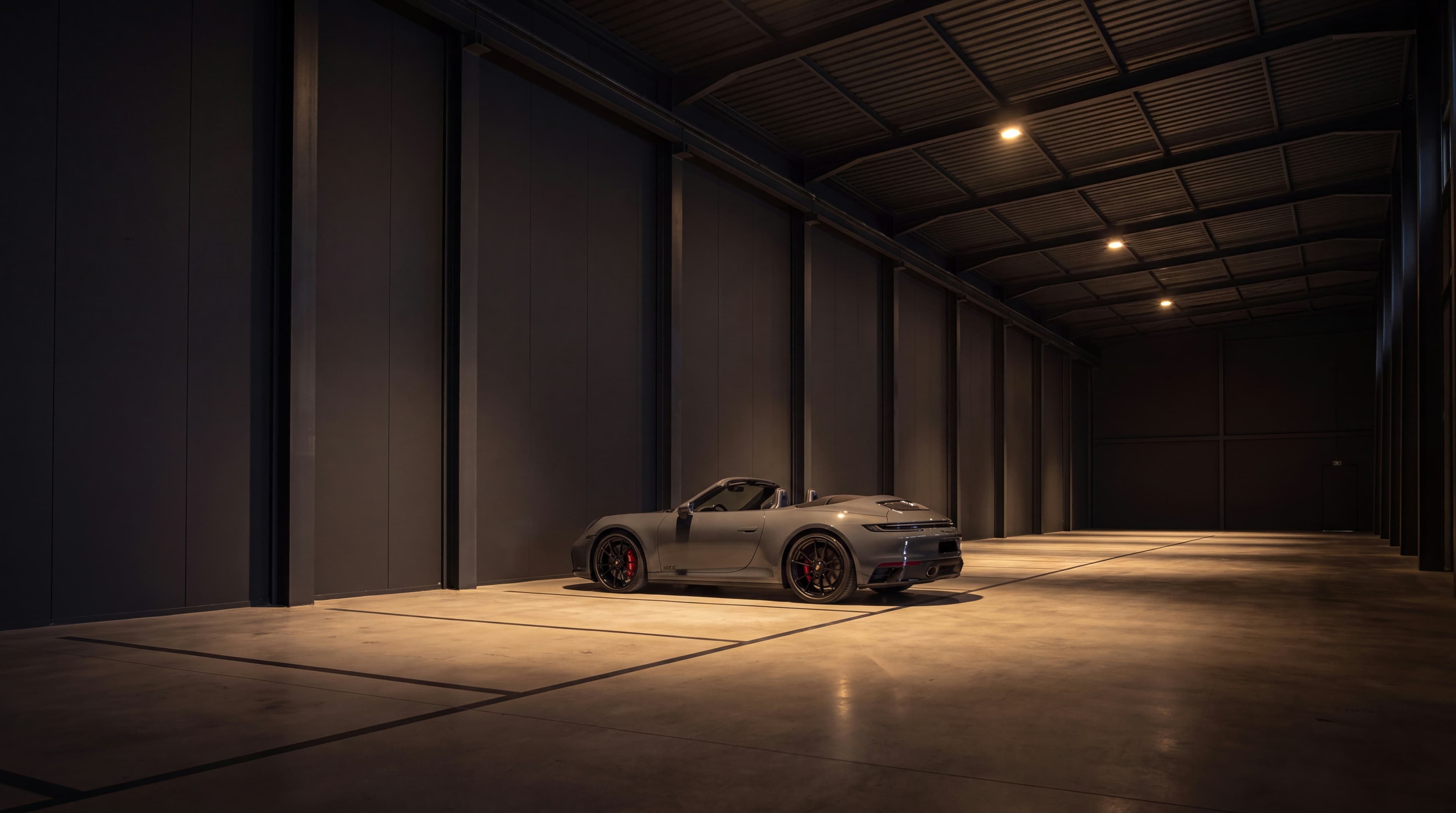 Grey Porsche 911 displayed alone in the dark gallery space of the Vault 620 vehicle preservation facility