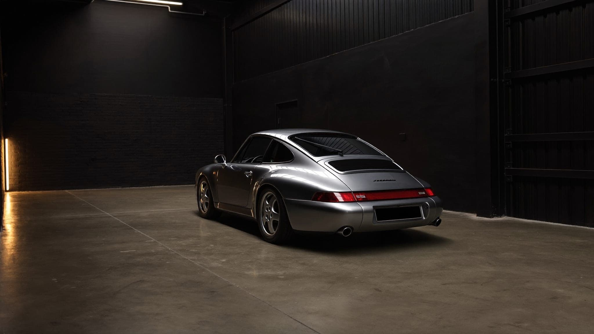 Silver Porsche 911 displayed alone in the dark gallery space of the Vault 620 vehicle preservation facility